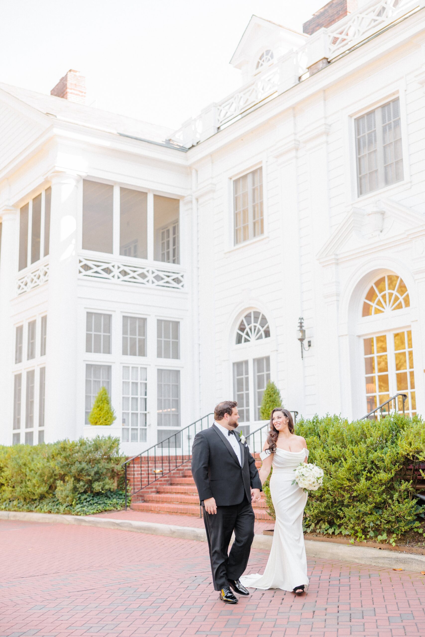 Meg and Tyler walk hand in hand through the grounds of Duke Mansion.