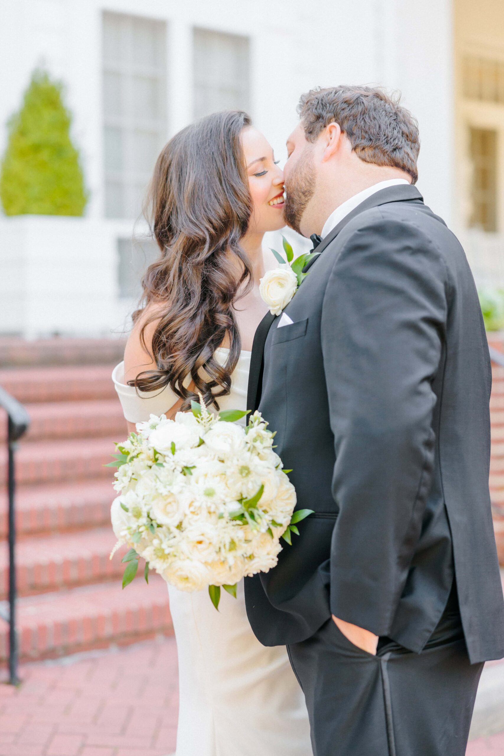 Bride and groom kiss in front of the Duke Mansion before their wedding ceremony.