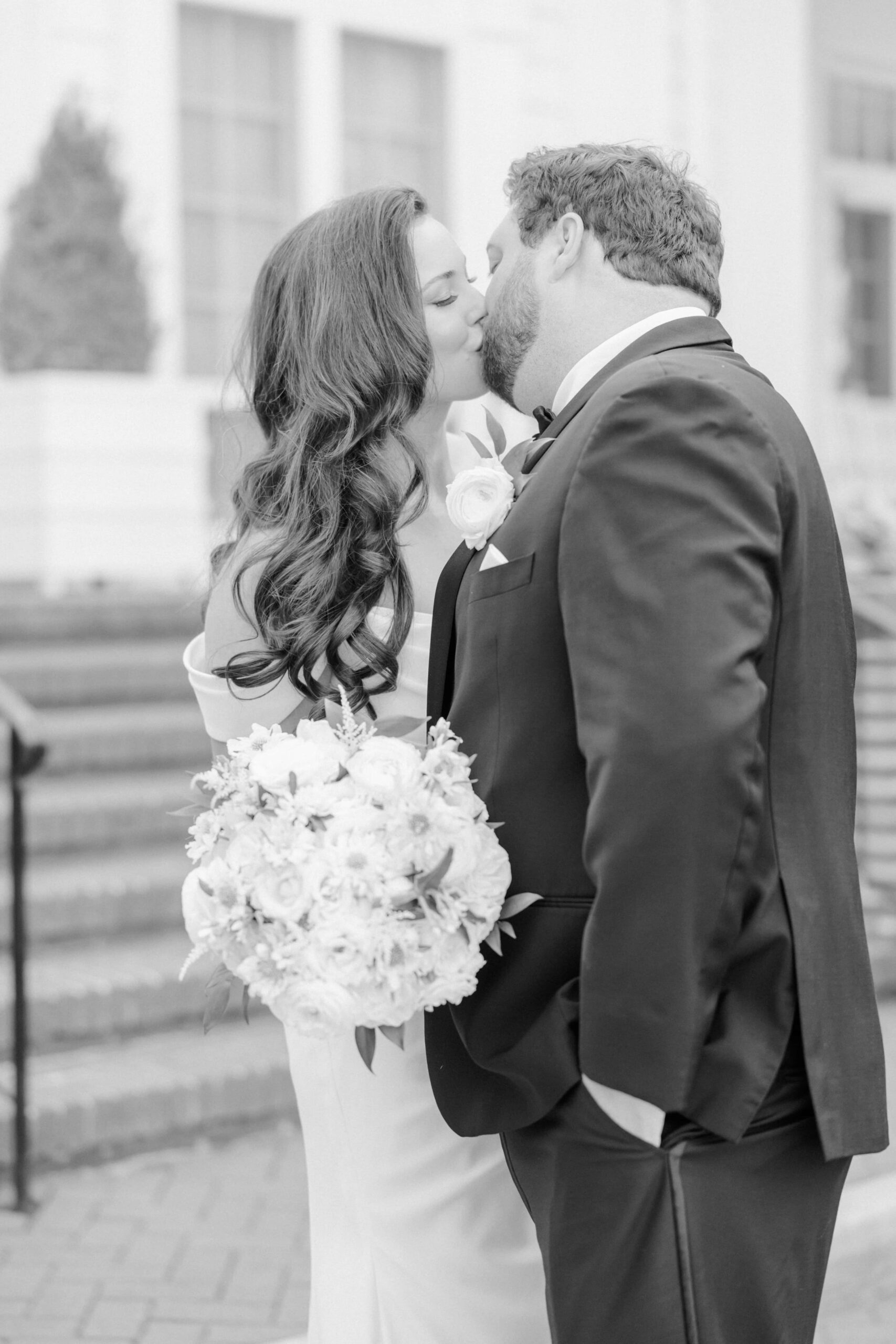 Meg and Tyler kiss for a wedding picture at the front of the Duke Mansion venue.