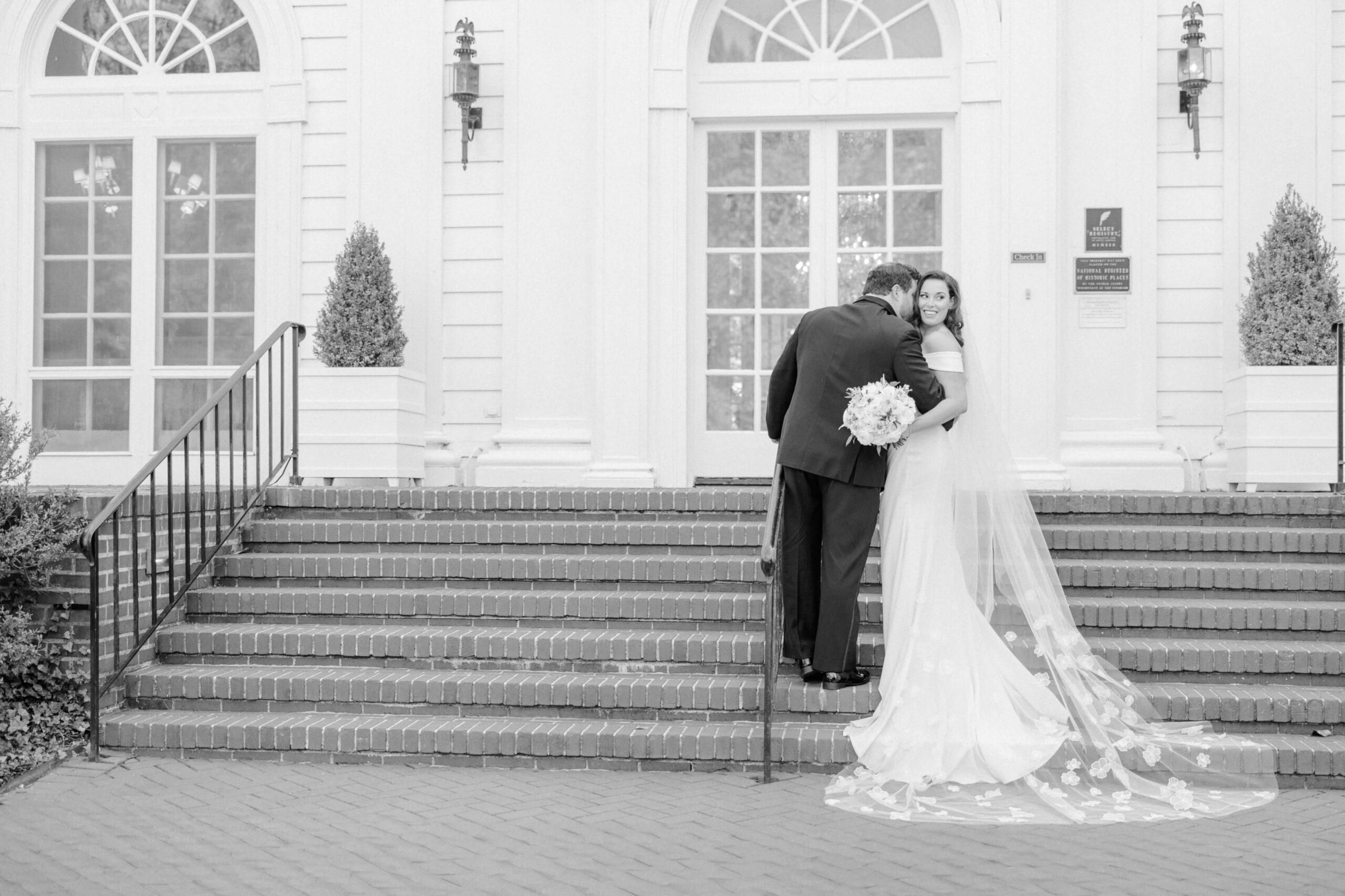 The Duke Mansion front steps show Meg and Tyler snuggling up together in their wedding attire.