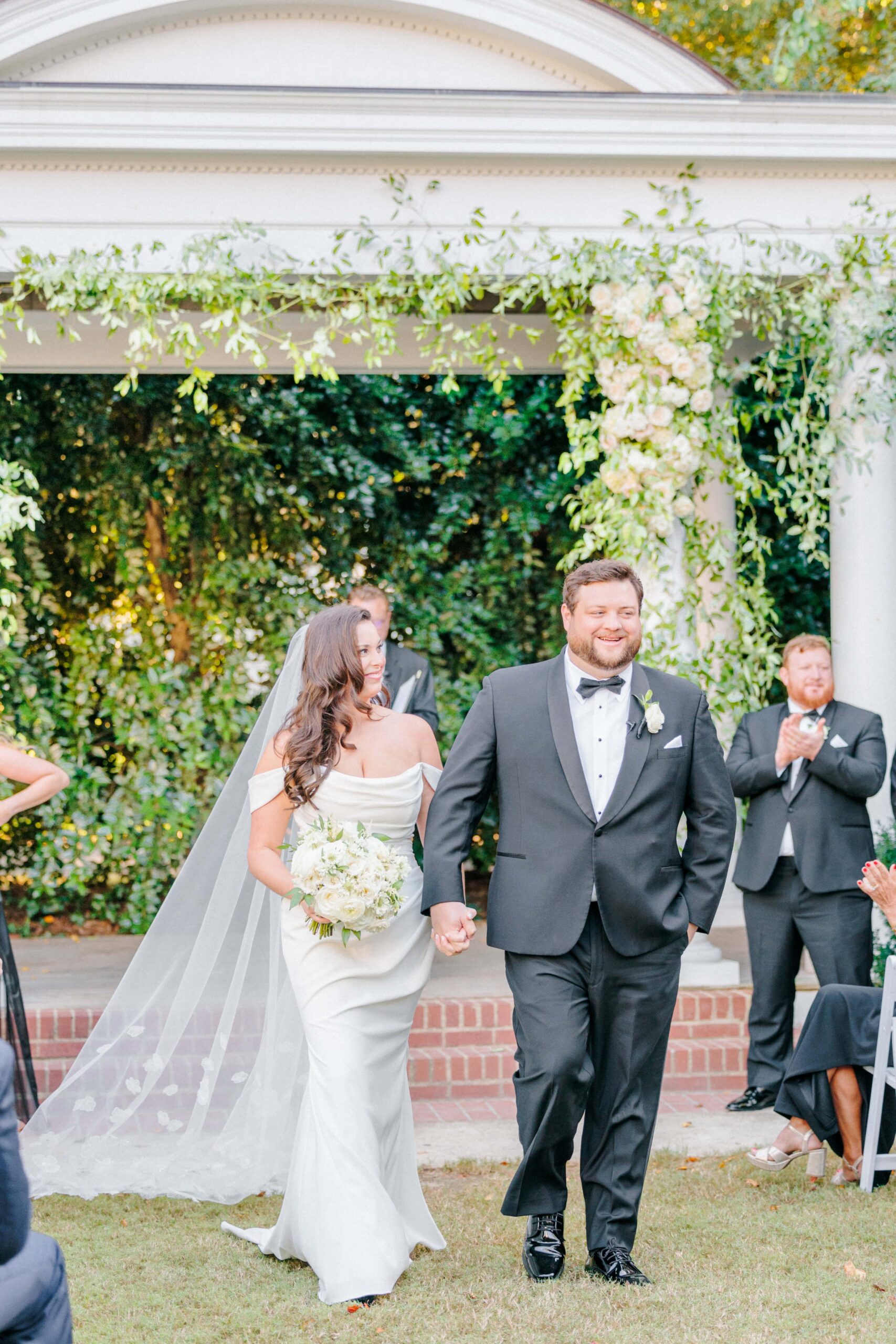 Bride and groom walk down the Duke Manion aisle with the gazebo in the background after just being married.