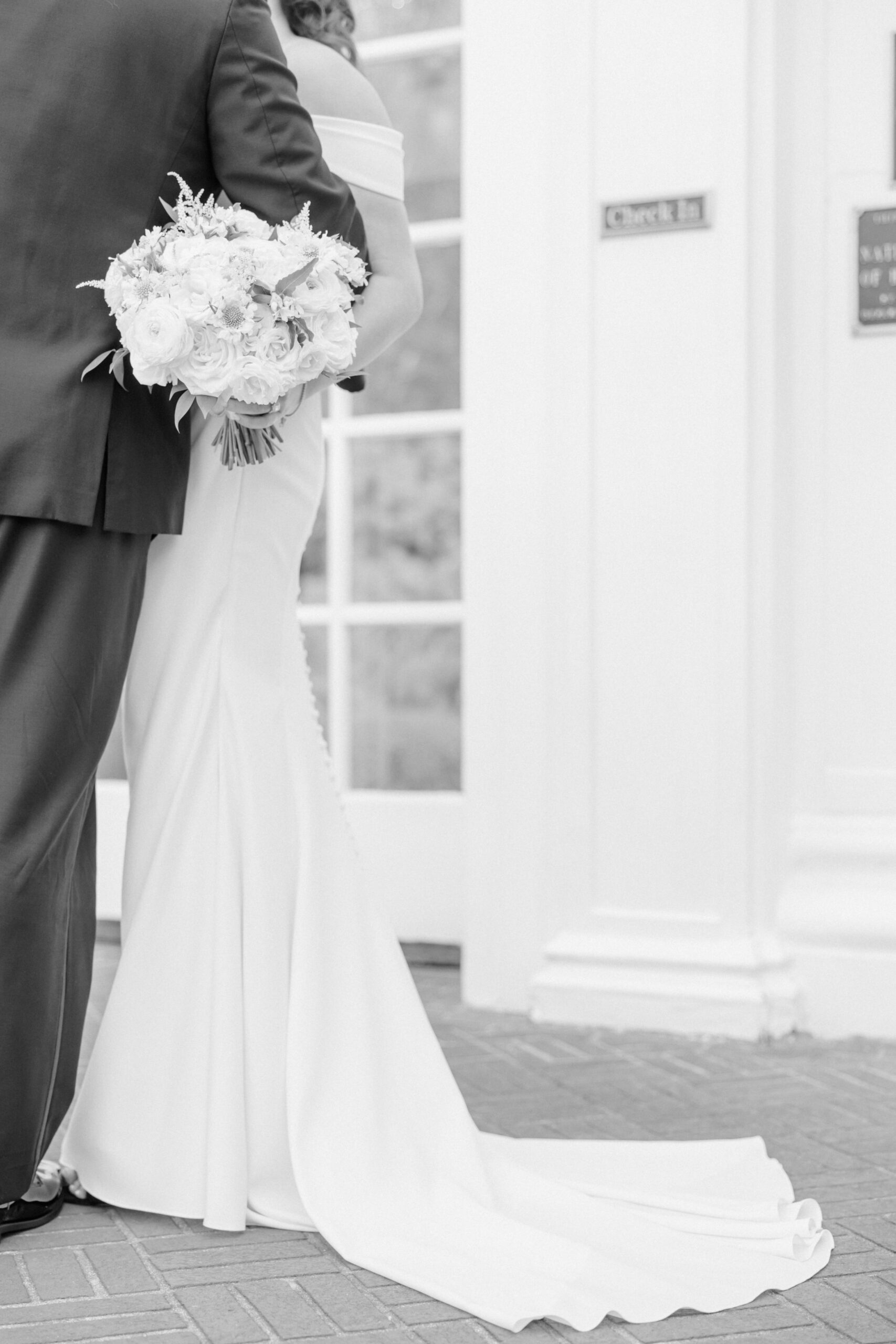 The bride holds her bouquet to her side as the train of her wedding dress trails on the floor of the Duke Mansion.